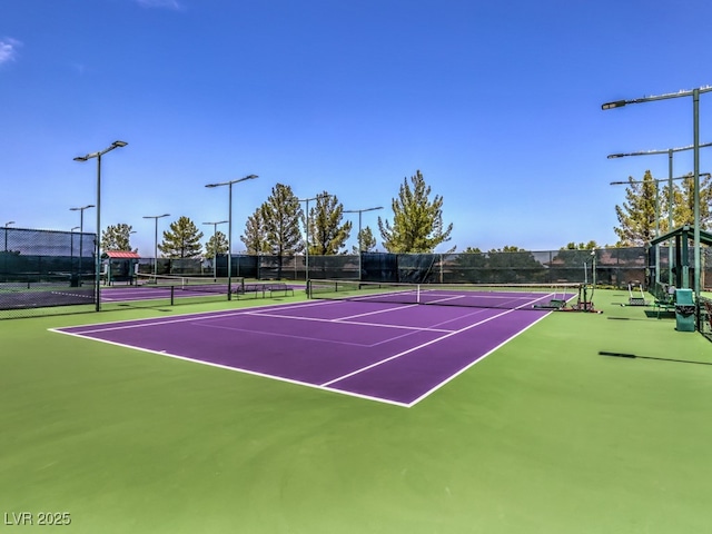 view of tennis court featuring community basketball court and fence