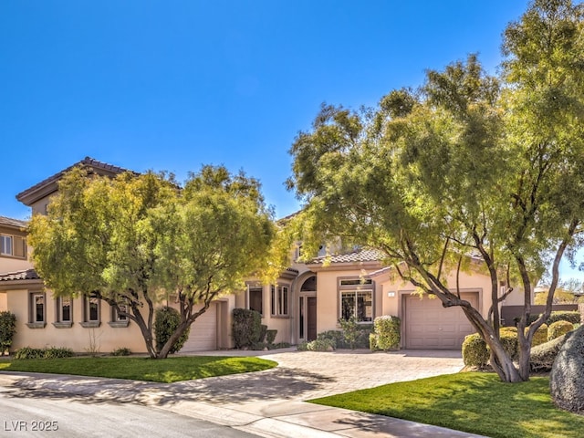 view of front facade featuring decorative driveway, stucco siding, a front yard, a garage, and a tiled roof