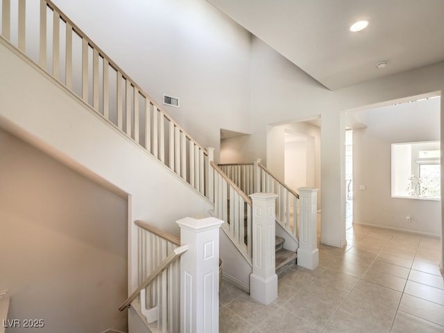 stairs featuring tile patterned floors, a high ceiling, visible vents, and recessed lighting