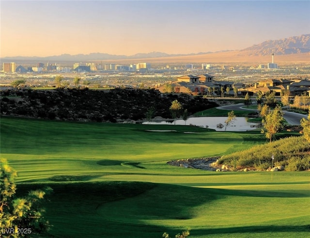 view of home's community with golf course view, a yard, and a water and mountain view