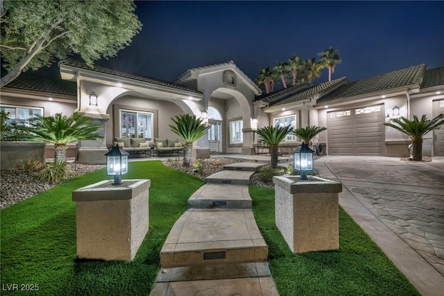 view of front facade featuring driveway, a tiled roof, an attached garage, and stucco siding