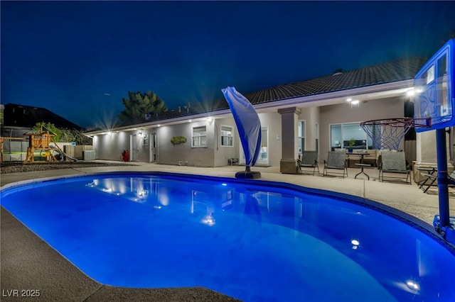 pool at twilight featuring an outdoor pool, a playground, and a patio