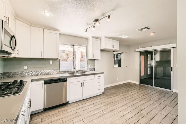 kitchen with stainless steel appliances, visible vents, backsplash, white cabinetry, and a sink