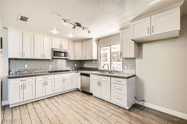 kitchen featuring a sink, visible vents, white cabinetry, appliances with stainless steel finishes, and wood tiled floor