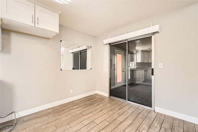 unfurnished room featuring a sink, baseboards, and wood finished floors