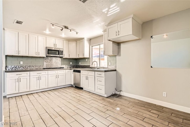 kitchen with white cabinets, stainless steel appliances, visible vents, and decorative backsplash