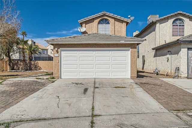 view of front of property with concrete driveway, an attached garage, a tiled roof, and stucco siding