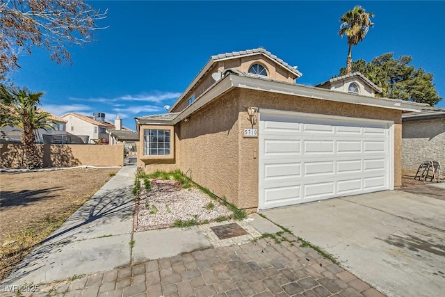 view of front of home featuring driveway, a garage, fence, and stucco siding