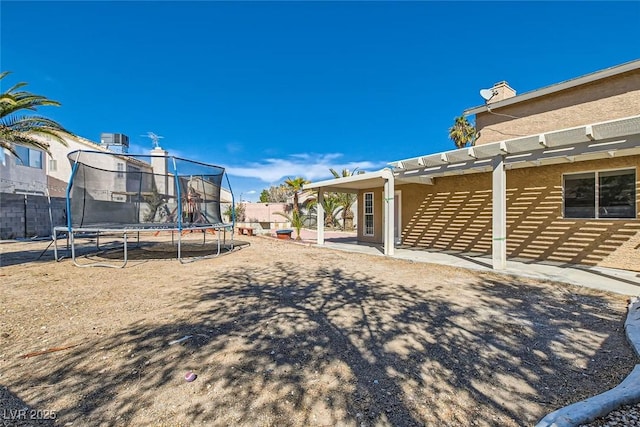 view of yard with a trampoline, fence, and a pergola