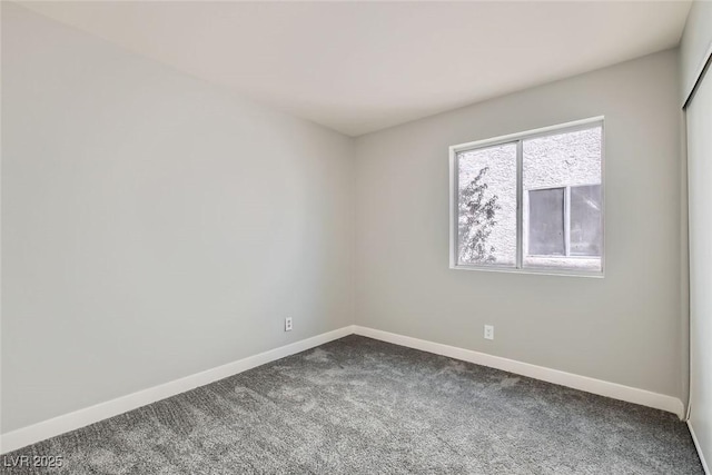 empty room with dark colored carpet and baseboards