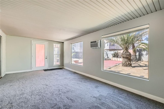 empty room with carpet, an AC wall unit, and baseboards