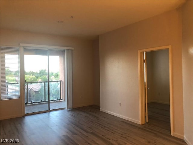 spare room with baseboards and wood finished floors