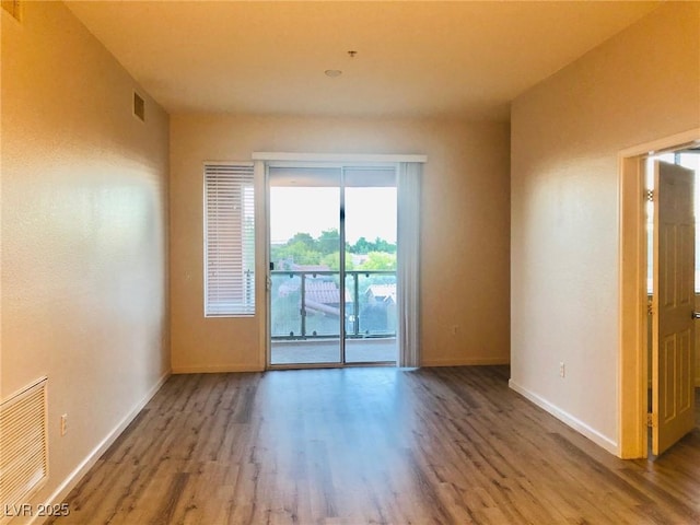 empty room with visible vents, baseboards, and wood finished floors