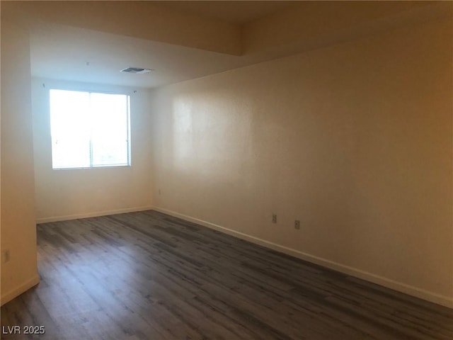 unfurnished room featuring visible vents, baseboards, and dark wood-style flooring