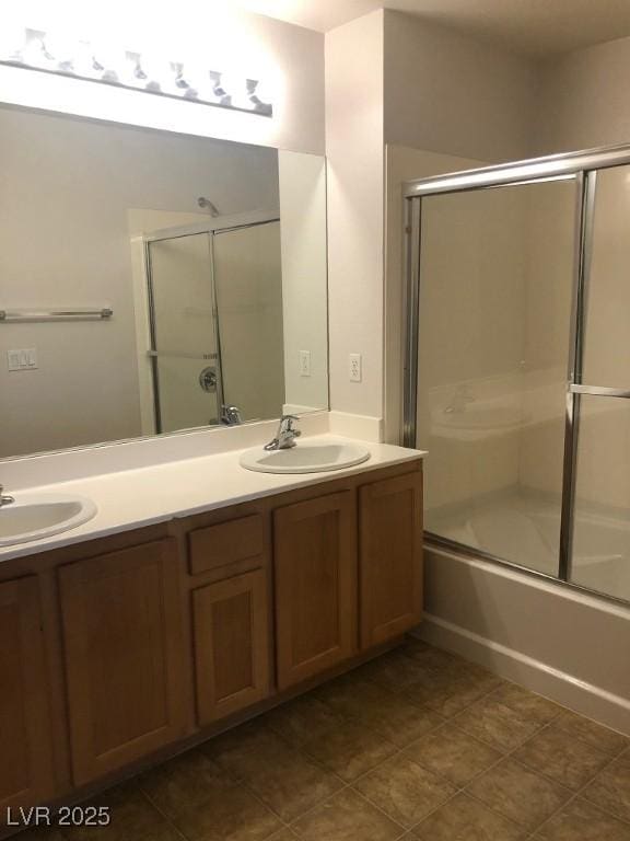 bathroom featuring double vanity, bath / shower combo with glass door, and a sink