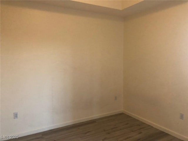 spare room with dark wood-style flooring and baseboards