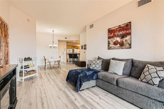 living room featuring light wood-style floors, a chandelier, and visible vents