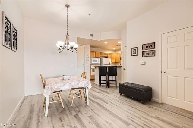 dining area with visible vents, a notable chandelier, baseboards, and light wood-type flooring