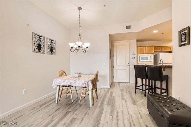 dining space with baseboards, visible vents, an inviting chandelier, and light wood-style floors