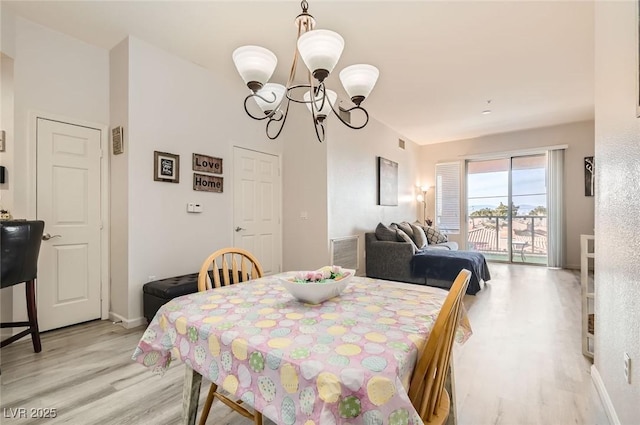 dining area with an inviting chandelier, light wood-type flooring, baseboards, and visible vents