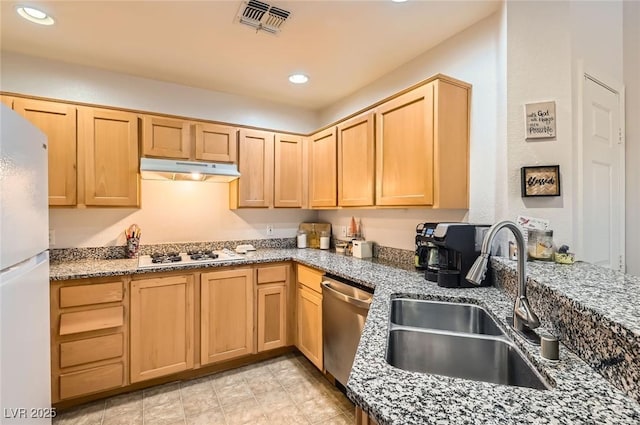 kitchen featuring visible vents, white appliances, under cabinet range hood, a sink, and light brown cabinetry