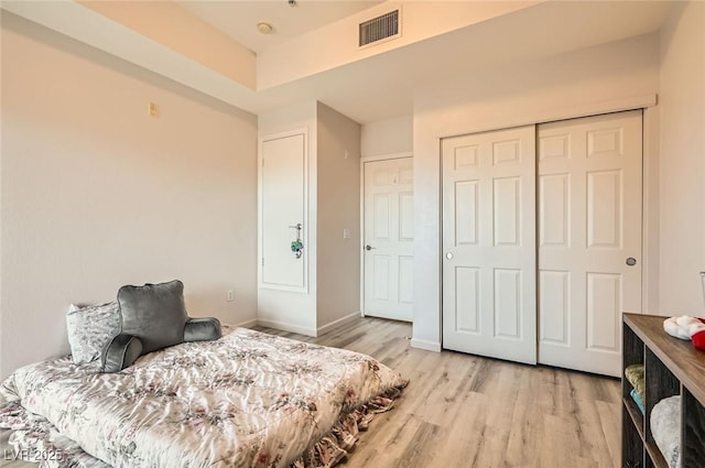 bedroom featuring a closet, baseboards, light wood-style flooring, and visible vents