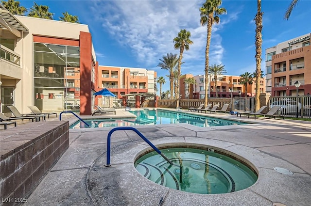 community pool with fence, a hot tub, and a patio