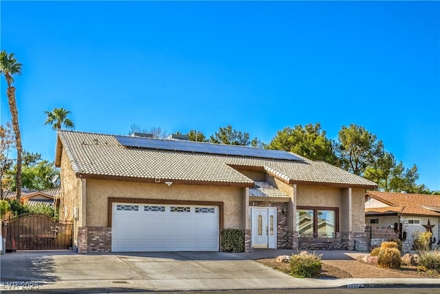 mediterranean / spanish-style home featuring a gate, a tile roof, an attached garage, and stucco siding