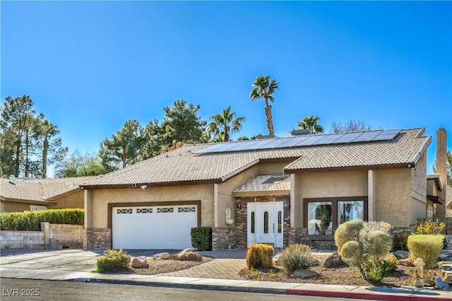 view of front of property with roof mounted solar panels, a tiled roof, an attached garage, and stucco siding