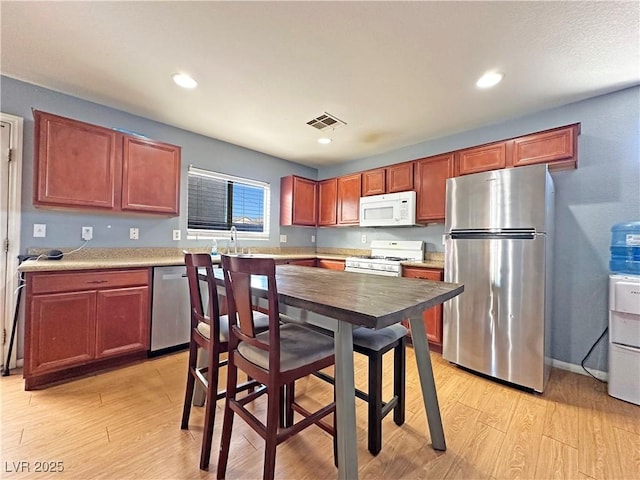 kitchen with stainless steel appliances, recessed lighting, visible vents, and light wood-style floors