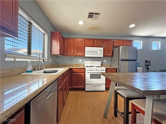 kitchen featuring stainless steel appliances, a sink, visible vents, light wood-type flooring, and a wealth of natural light