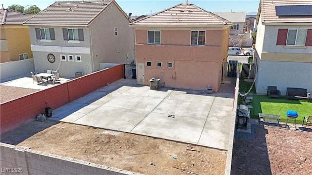 rear view of house with a fenced backyard, a tile roof, a residential view, stucco siding, and a patio area