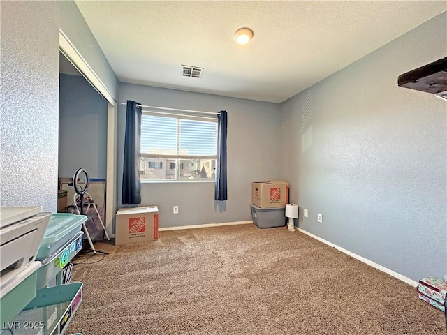 interior space with a textured ceiling, a textured wall, visible vents, baseboards, and carpet