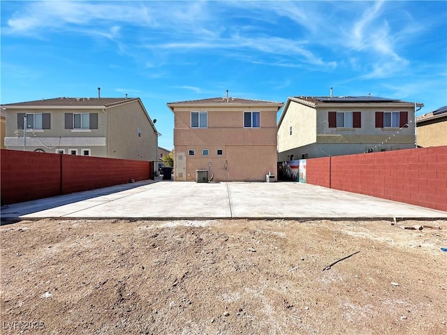 rear view of house with cooling unit, a patio area, fence, and stucco siding