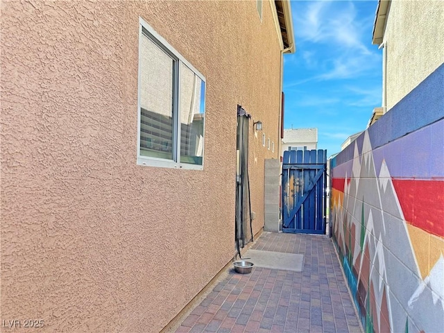 view of side of property featuring a gate and stucco siding