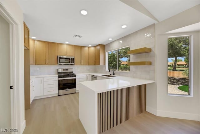 kitchen featuring stainless steel appliances, light countertops, a sink, and visible vents