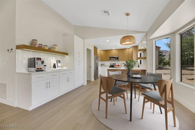 dining area featuring lofted ceiling, baseboards, visible vents, and light wood-style floors