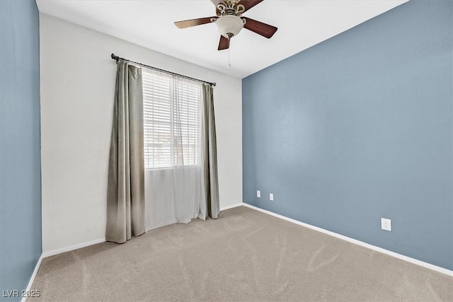 carpeted spare room with ceiling fan and baseboards