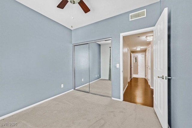 unfurnished bedroom featuring ceiling fan, visible vents, baseboards, a closet, and carpet