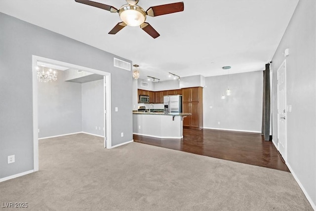 unfurnished living room with visible vents, dark carpet, a ceiling fan, a sink, and baseboards