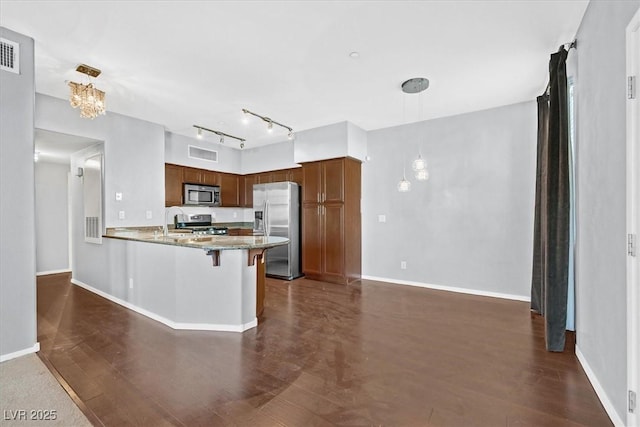 kitchen with baseboards, brown cabinets, dark wood-style flooring, a peninsula, and stainless steel appliances