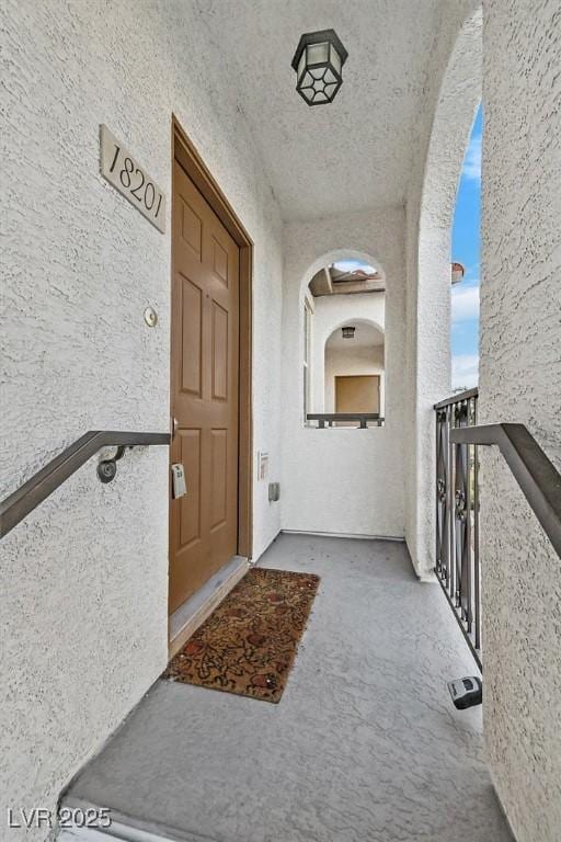 entrance to property featuring a balcony and stucco siding