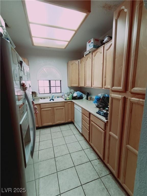 kitchen with light tile patterned floors, white dishwasher, light brown cabinets, light countertops, and stainless steel fridge