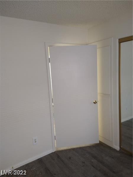 unfurnished room with dark wood finished floors and a textured ceiling