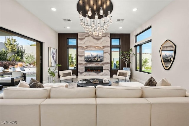 living room featuring a premium fireplace, visible vents, a notable chandelier, and recessed lighting