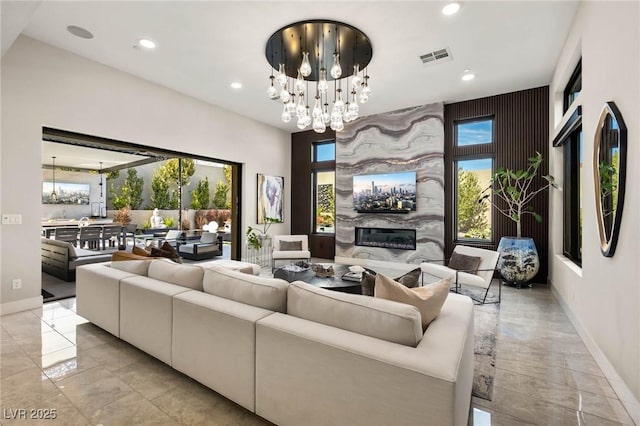 living area featuring recessed lighting, a notable chandelier, a premium fireplace, visible vents, and marble finish floor