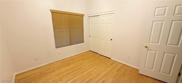 unfurnished bedroom featuring light wood-type flooring, a closet, and baseboards