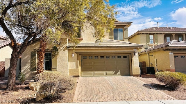 view of front of property with a garage, central AC, decorative driveway, and stucco siding