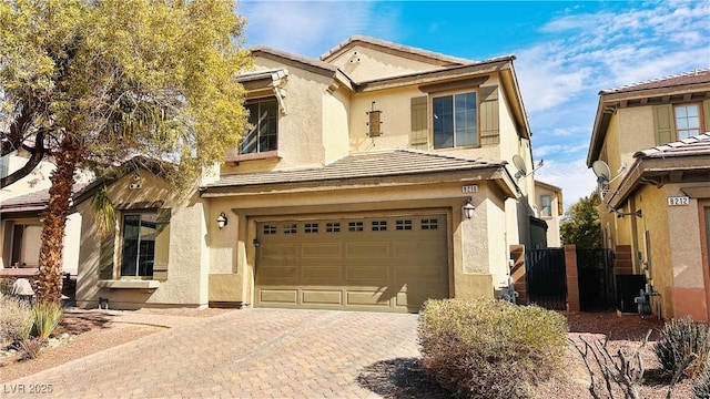 view of front of home featuring a tiled roof, decorative driveway, an attached garage, and stucco siding