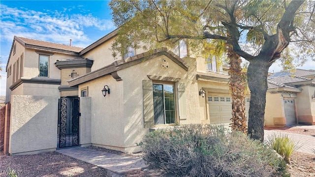 view of front of home with a garage, a gate, and stucco siding